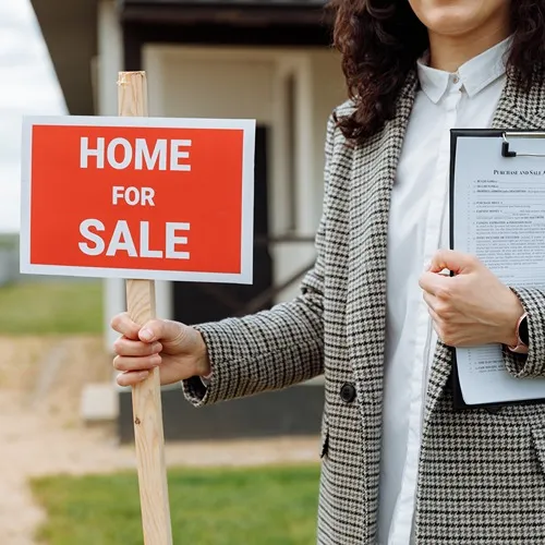 real estate agent holding a for sale sign